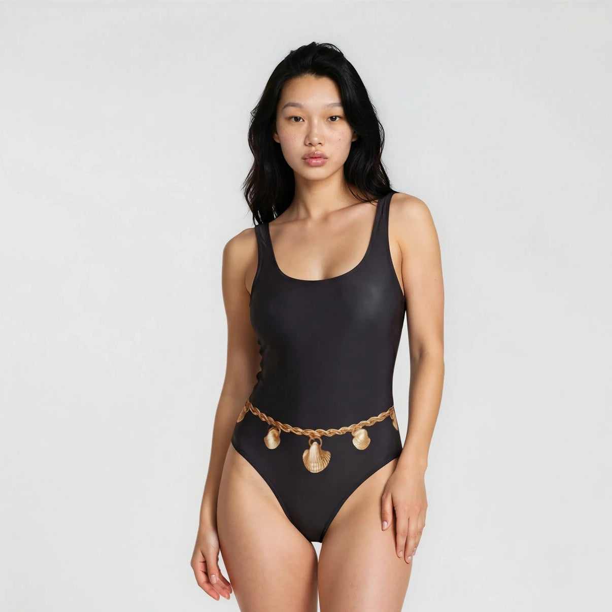 Woman wearing a black swimsuit with gold accents on a white background