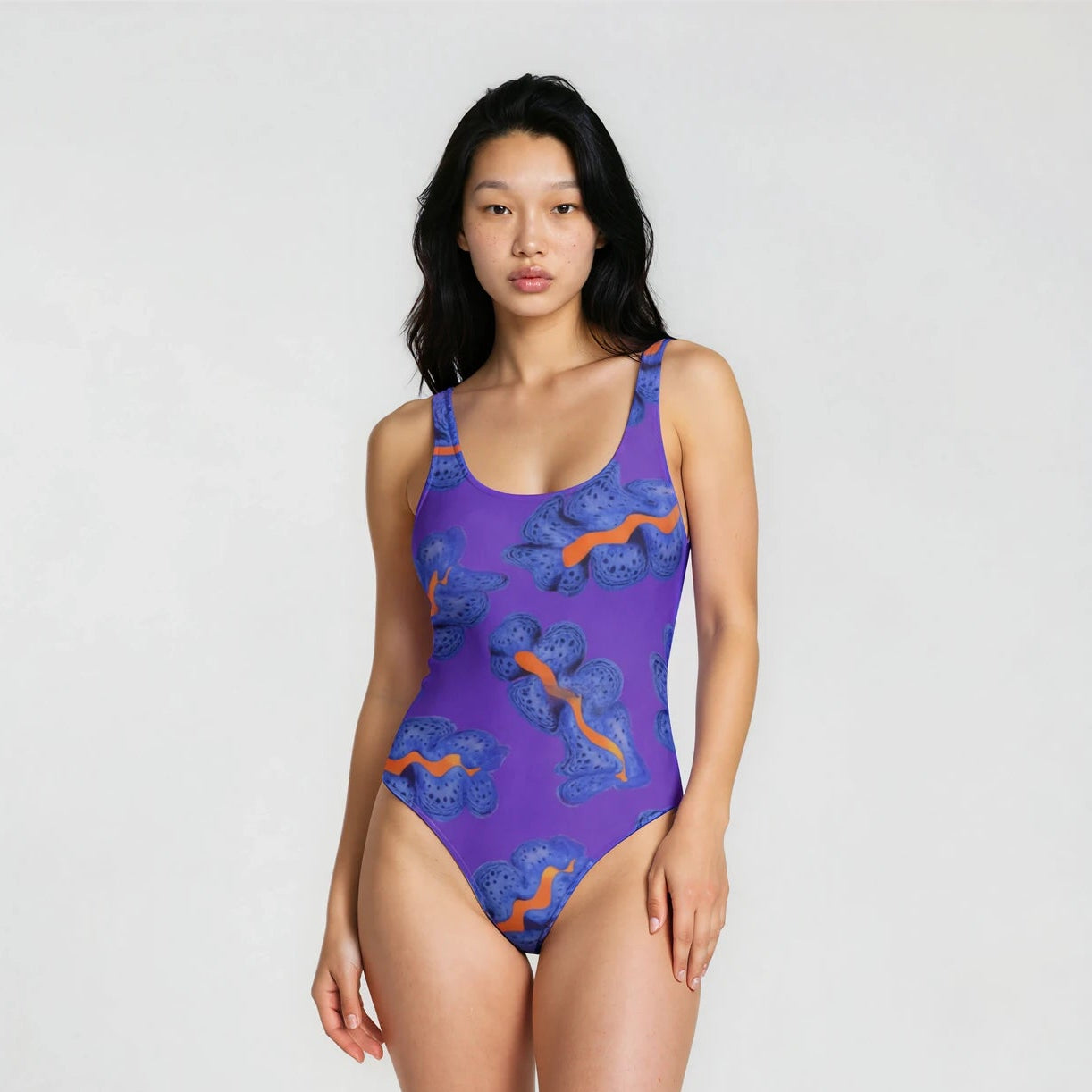 Woman wearing a purple swimsuit with orange patterns on a white background