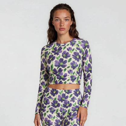 Woman wearing a purple floral long-sleeve top and shorts on a white background