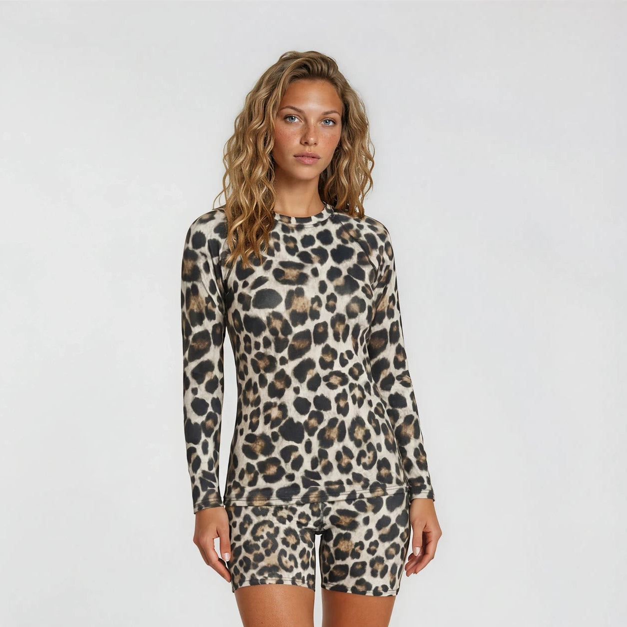 Woman wearing a leopard print long-sleeve romper on a white background