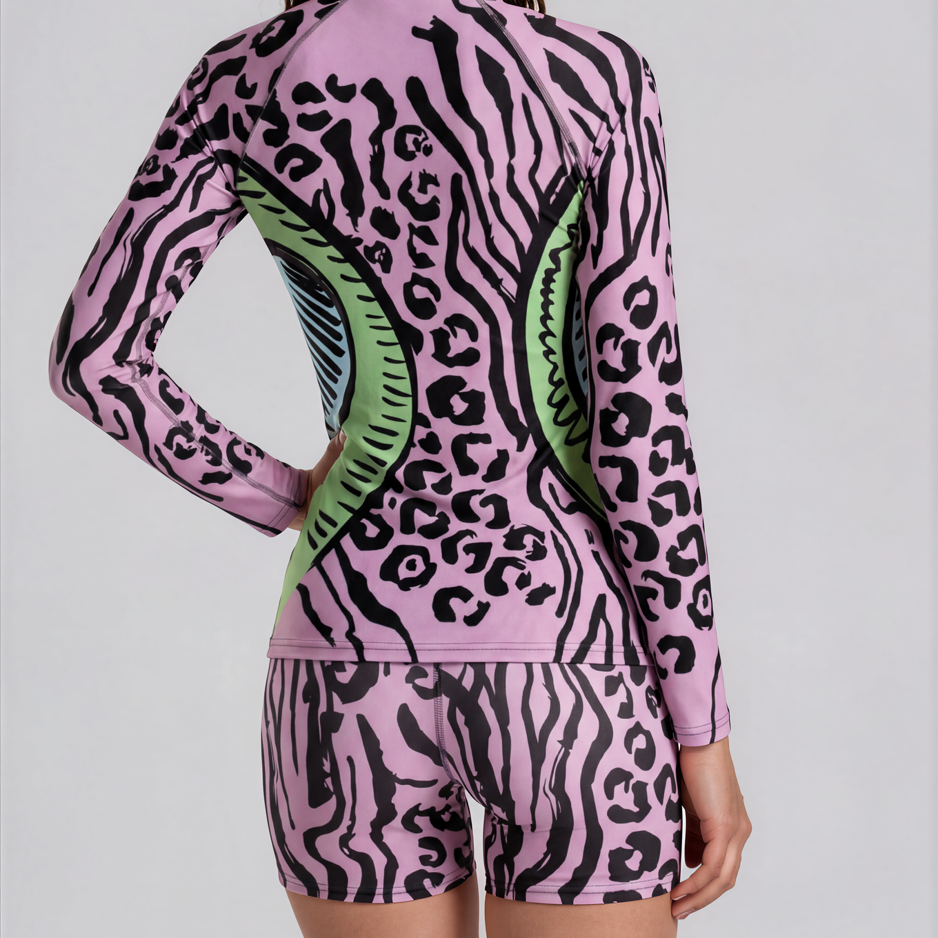 Person wearing a pink and black animal print outfit with green accents on a plain background