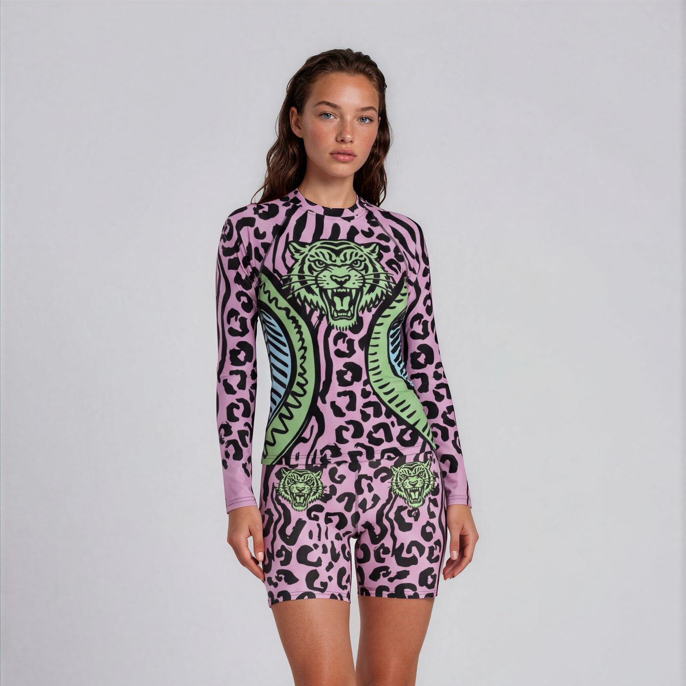 Person wearing a pink leopard print onesie with green accents on a white background